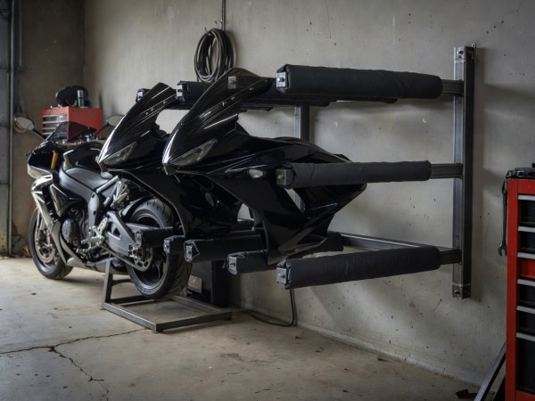 Padded wall storage arms holding removed motorcycle side fairings safely off the garage floor